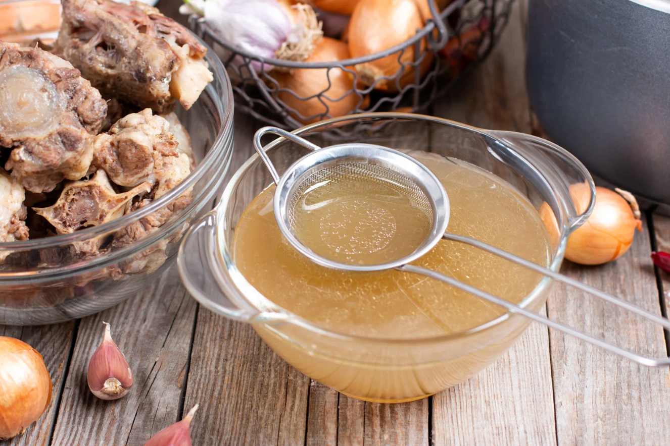 both broth in glass bowl on wooden table