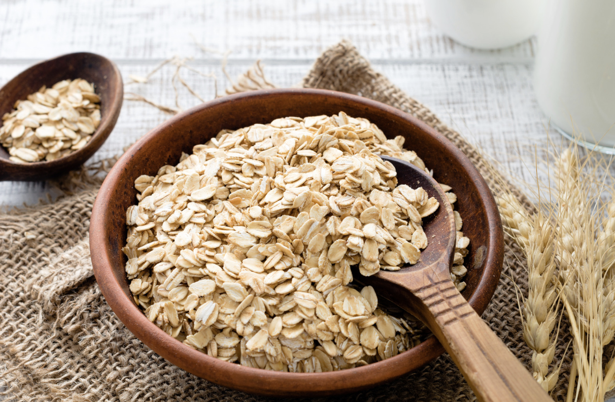 wooden bowl of oats with wooden spoon on table
