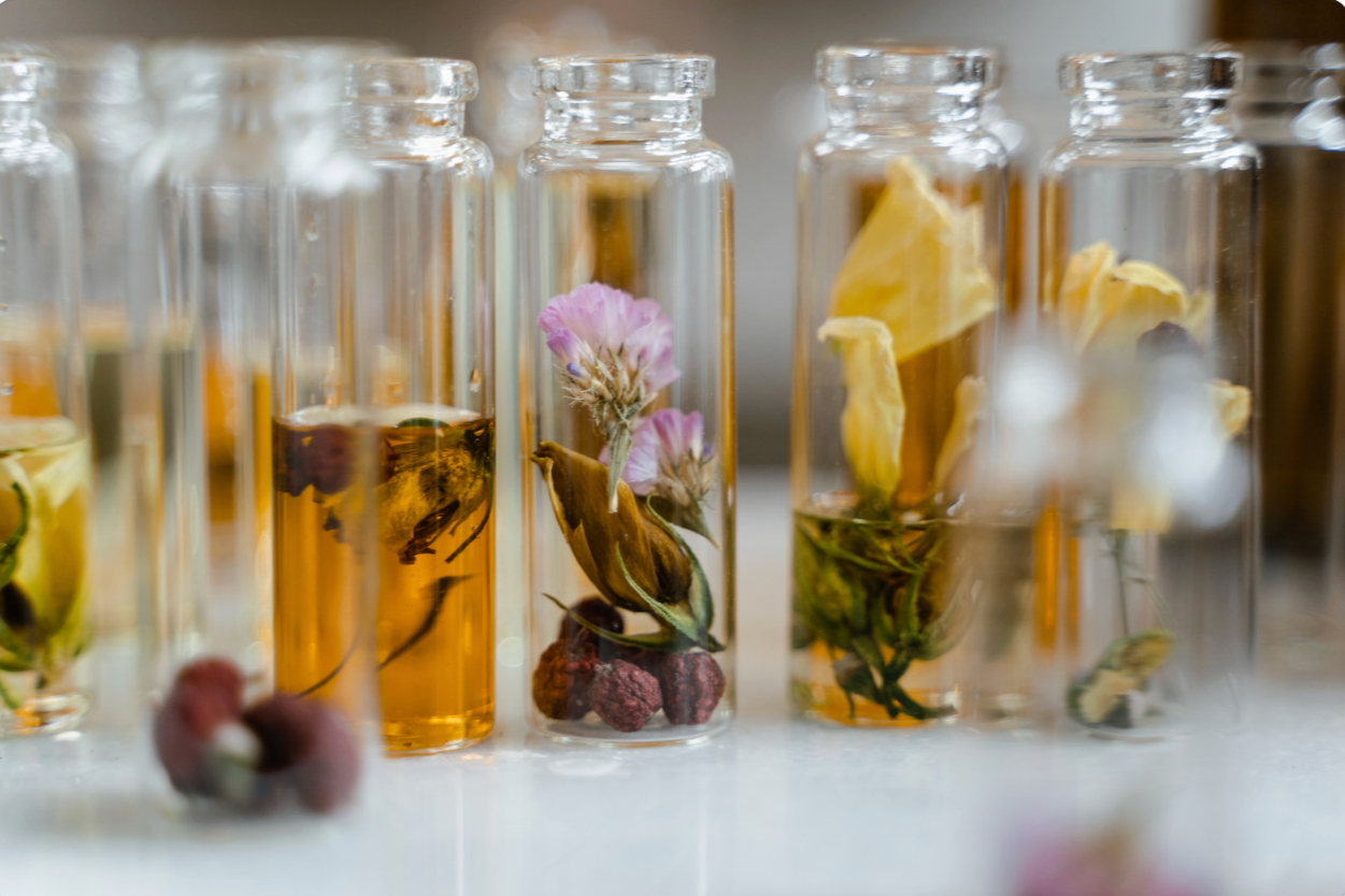 clear jars of fruits and flowers in oil