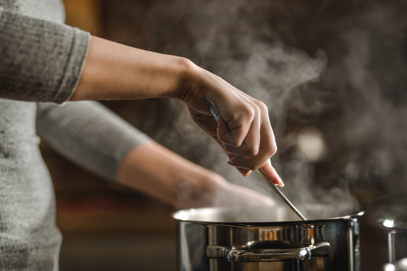 woman stirring a pot of steaming broth
