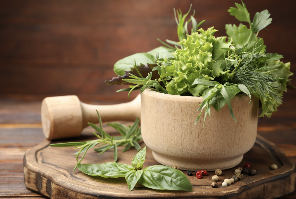 group of fresh cut herbs in wooden pestle