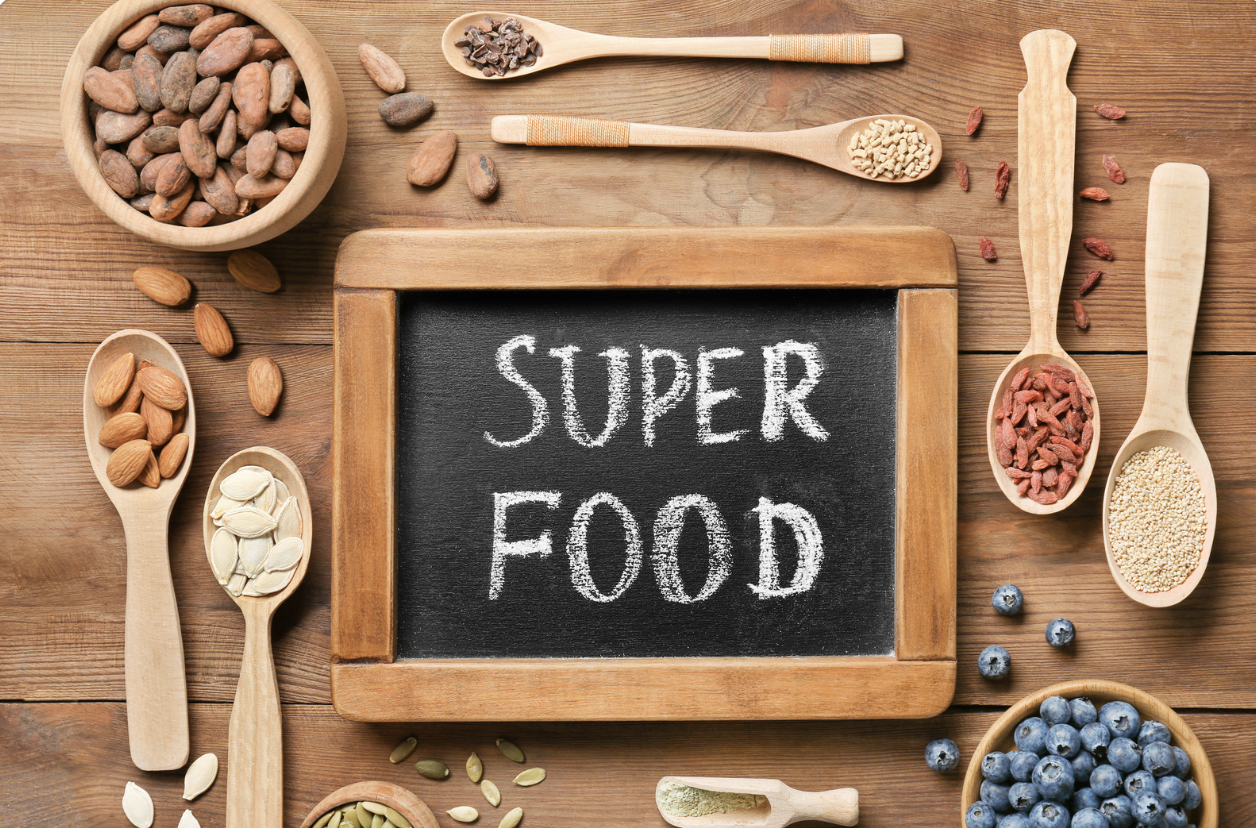 super food sign on chalkboard tablet with food in spoons and bowls on table