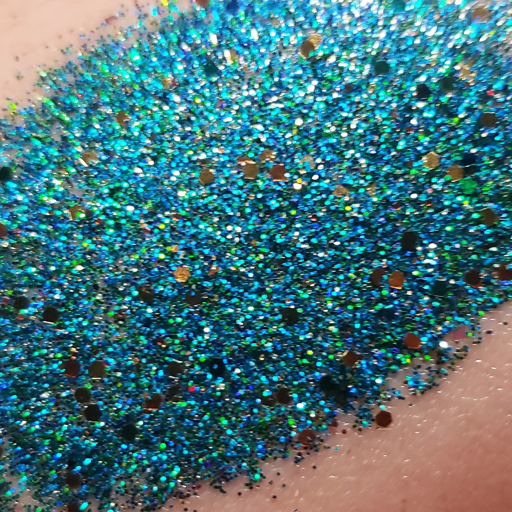 Sparkling array of blue teal turquoise green with flecks of gold and silver for a shimmering dramatic plant based glitter cream in a vegan non toxic formula dries to a water resistant  powder finish
