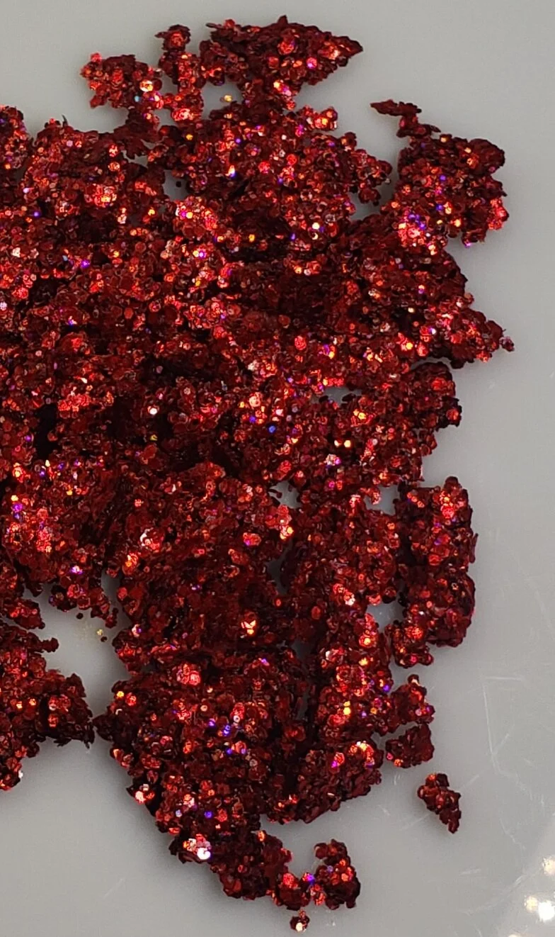 Rich ruby red shimmer with sparkling violet plant based glitter cream in a vegan and non toxic formula dries to a water resistant powder finish