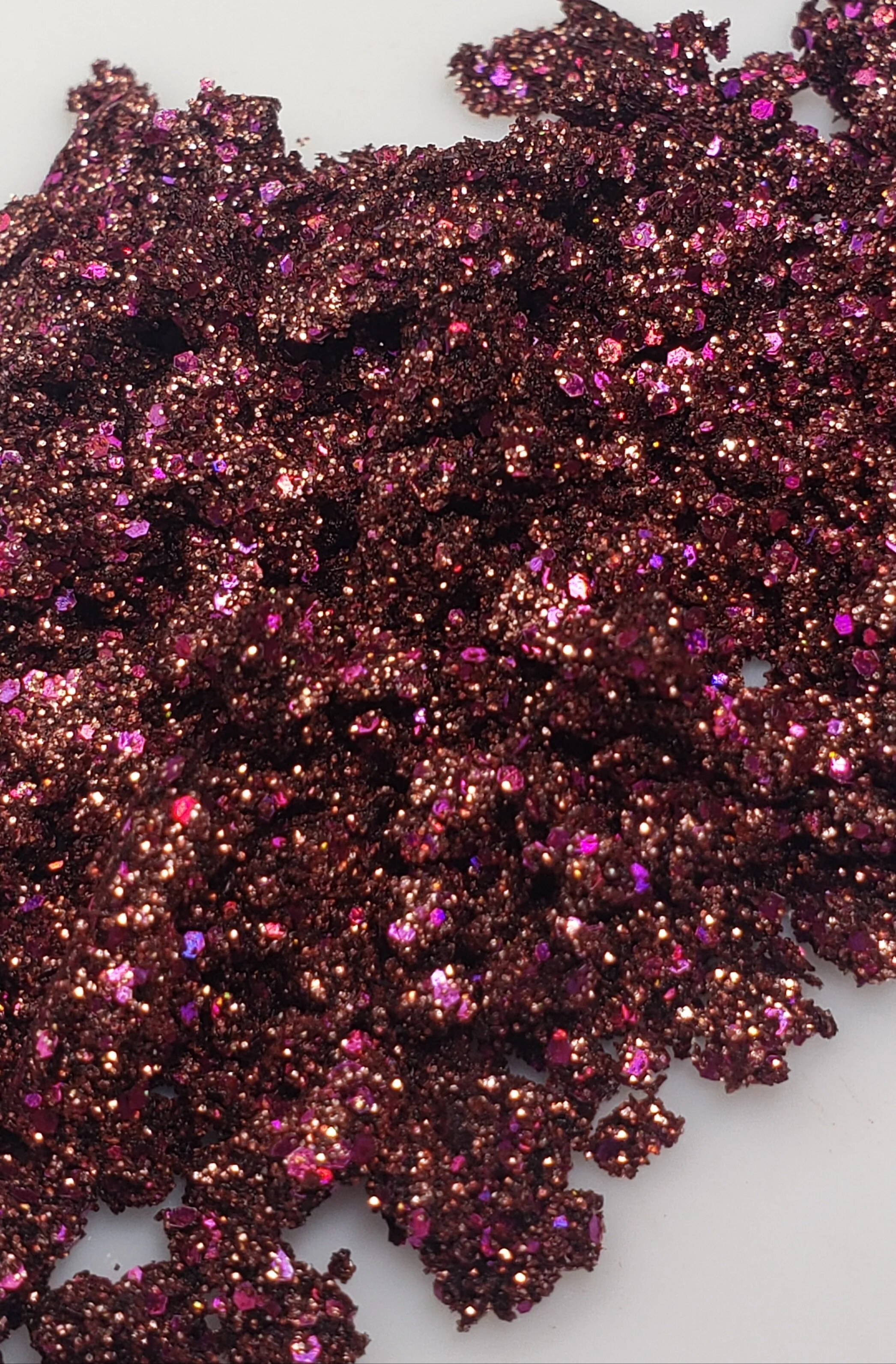 Sparkling bronze and pink with silver flecks of shimmering plant based glitter cream in a vegan and non toxic formula dries to a water resistant powder finish