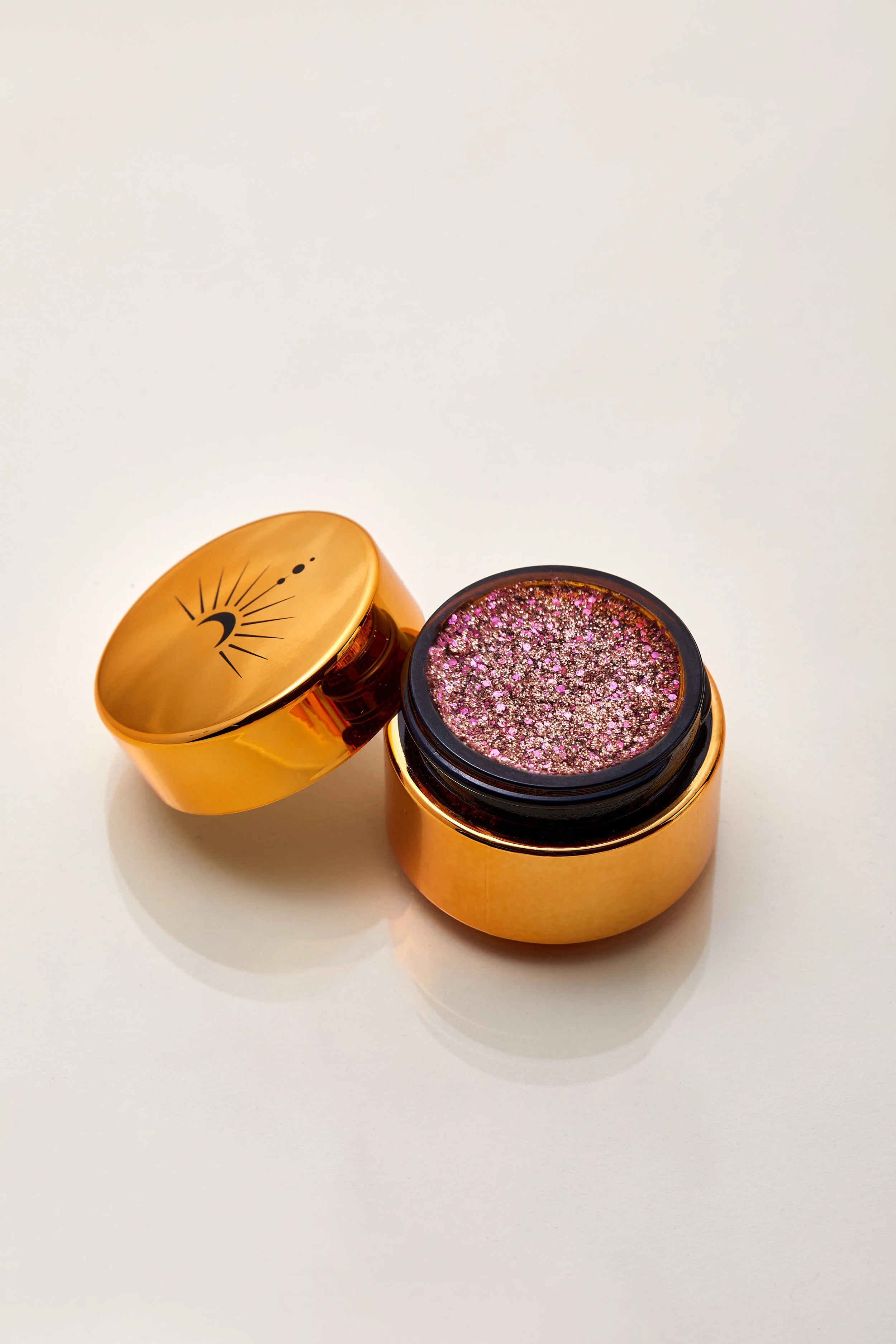 Sparkling bronze and pink with silver flecks of shimmering plant based glitter cream in a vegan and non toxic formula dries to a water resistant powder finish