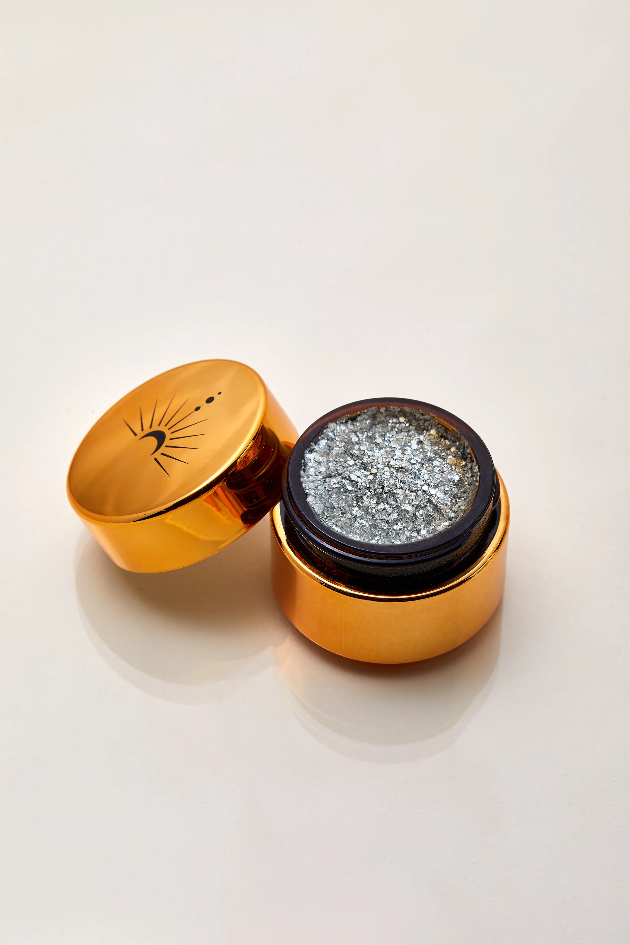 Sparkling champagne silver shimmering plant based glitter cream in a vegan and non toxic formula dries to a water resistant powder finish