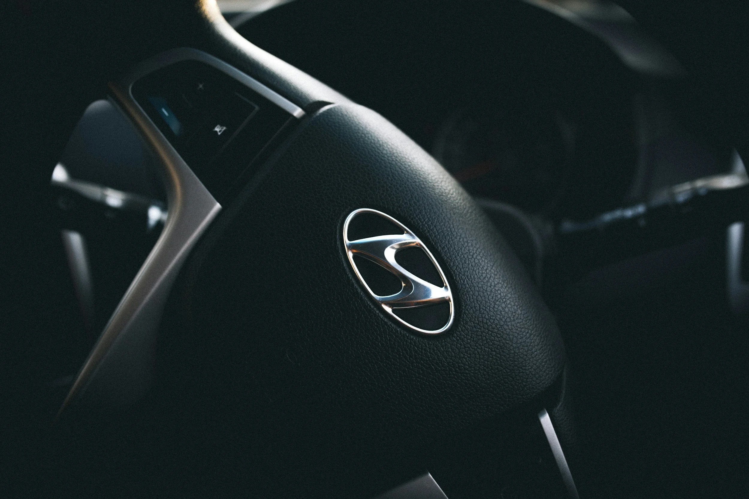 Close-up of a car's steering wheel with Honda logo, black textured surface, and part of the dashboard visible.