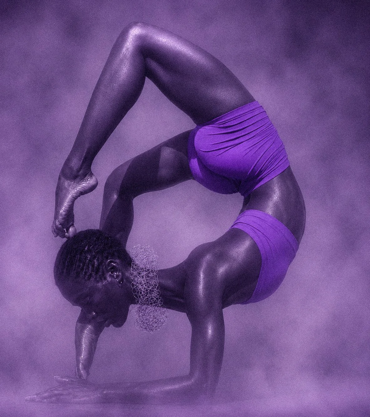 A person performing a yoga pose in a purple outfit with purple lighting effects.