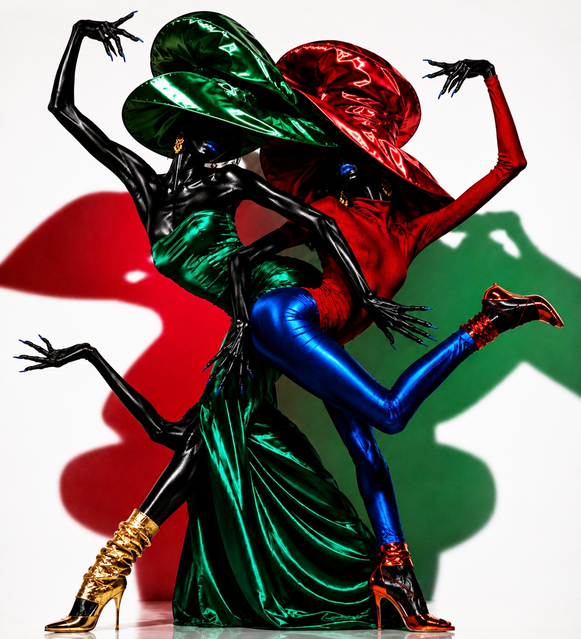 Two models dressed in shiny, colorful outfits with oversized hat accessories, striking dynamic poses against a white background with red and green shadows.