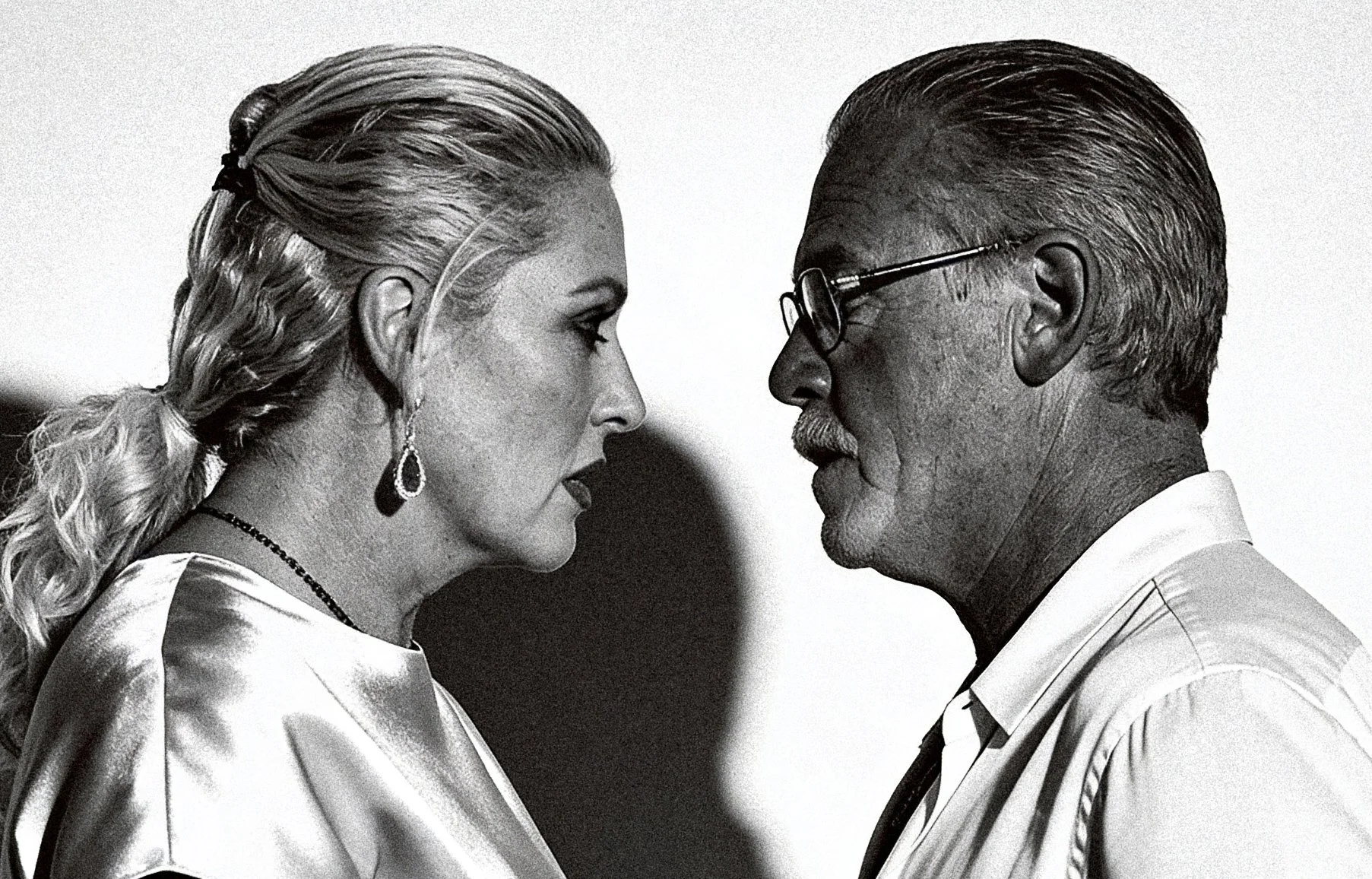 A black and white photo of a man and woman facing each other closely, about to kiss, with serious expressions.