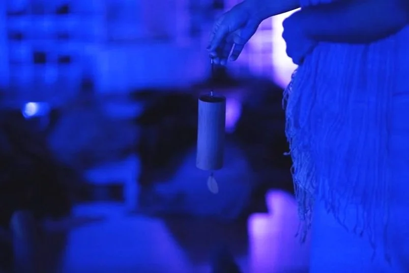 Person holding a koshi chime in a dim, blue-lit environment.