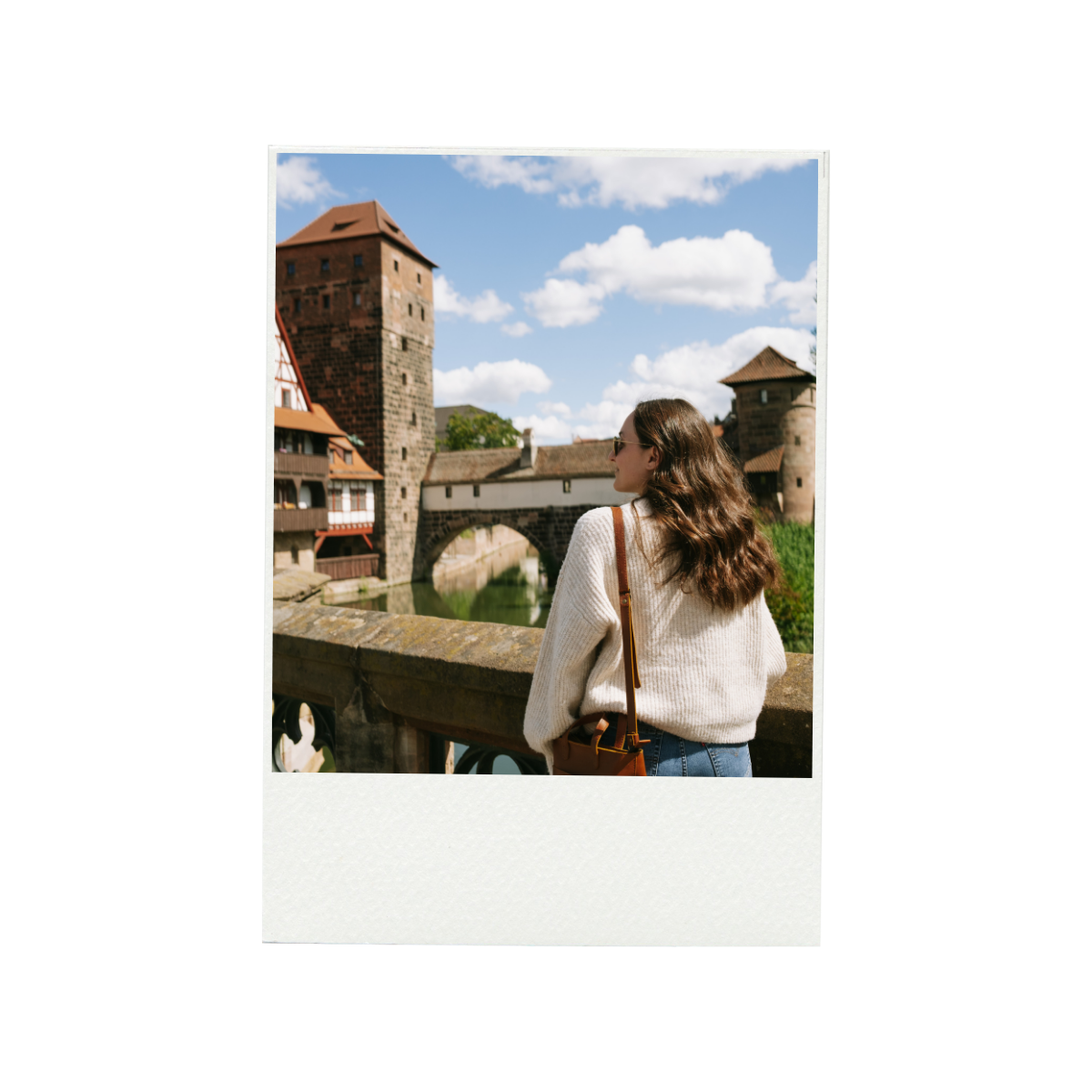 A hillside town with stone buildings, narrow streets, and lush greenery under a blue sky.
