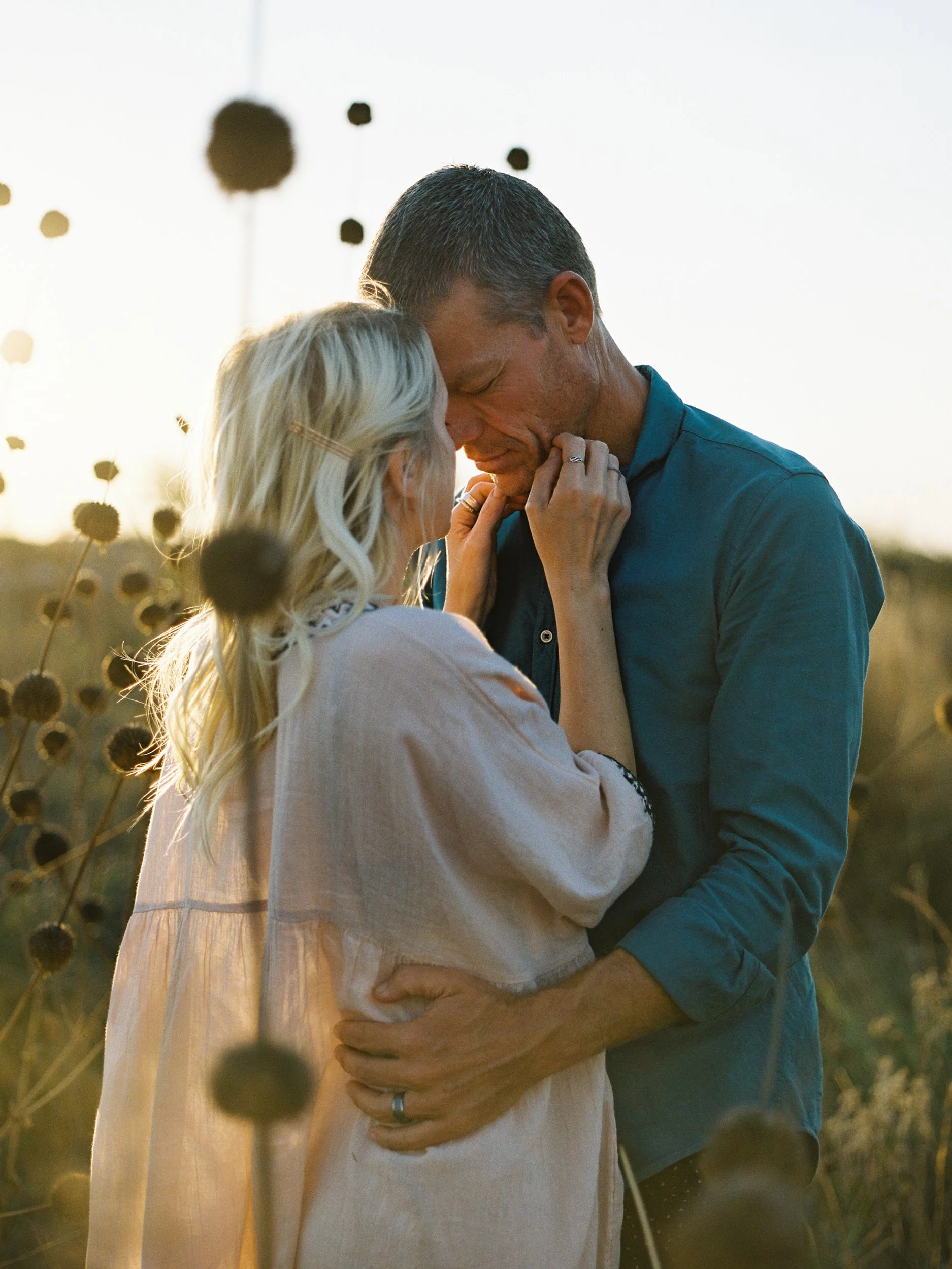 Un couple s'embrasse tendrement en plein air au coucher du soleil.