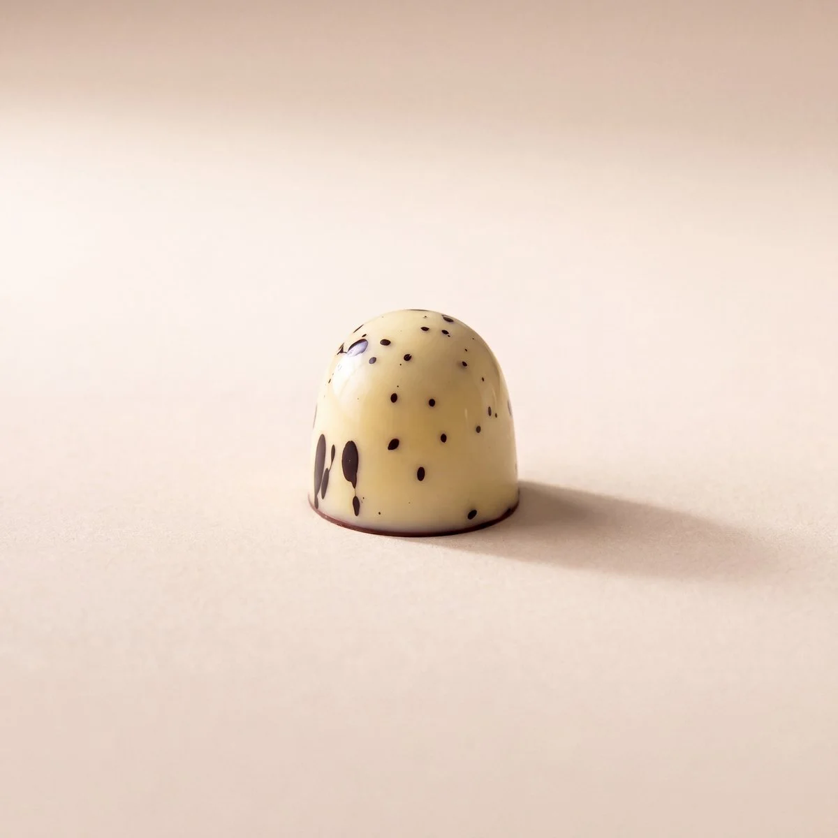 Yogurt and Vanilla bonbon, white chocolate shell with dark speckles
