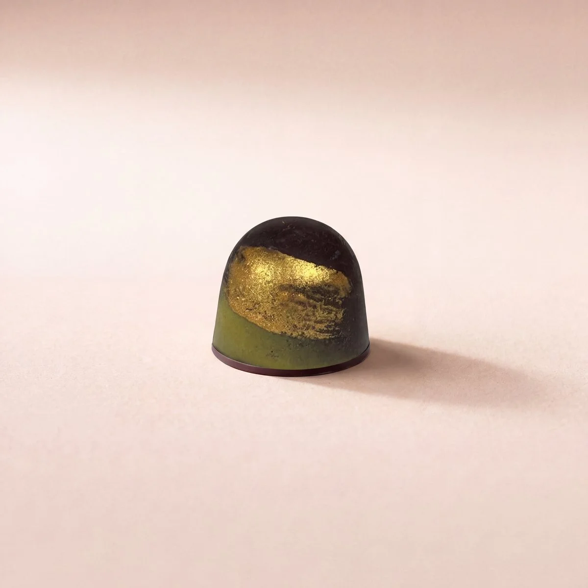Almond Praline bonbon with Puglia olive oil, dark shell with gold leaf