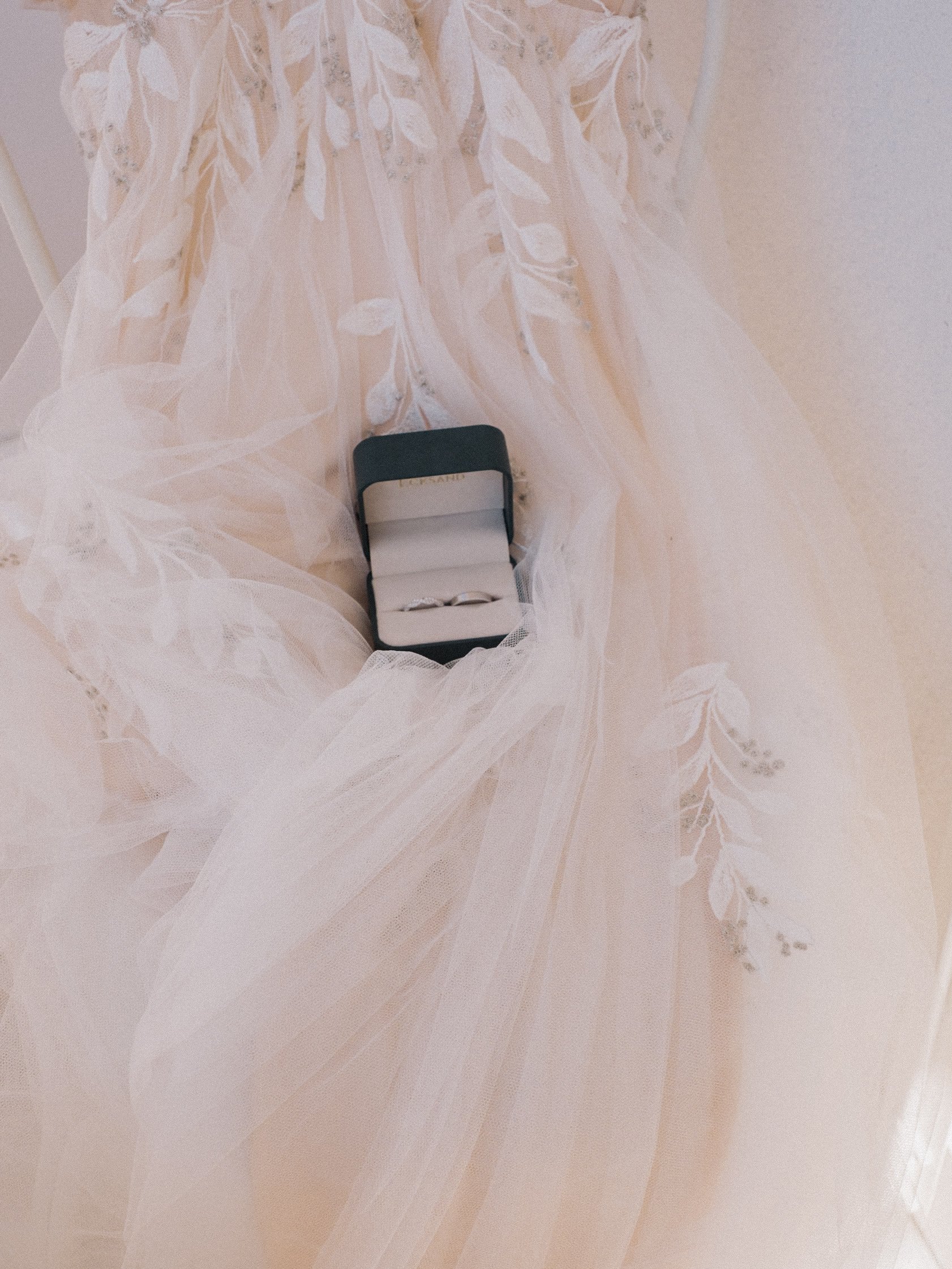 white wedding dress with embroidery and a jewelry box containing a ring