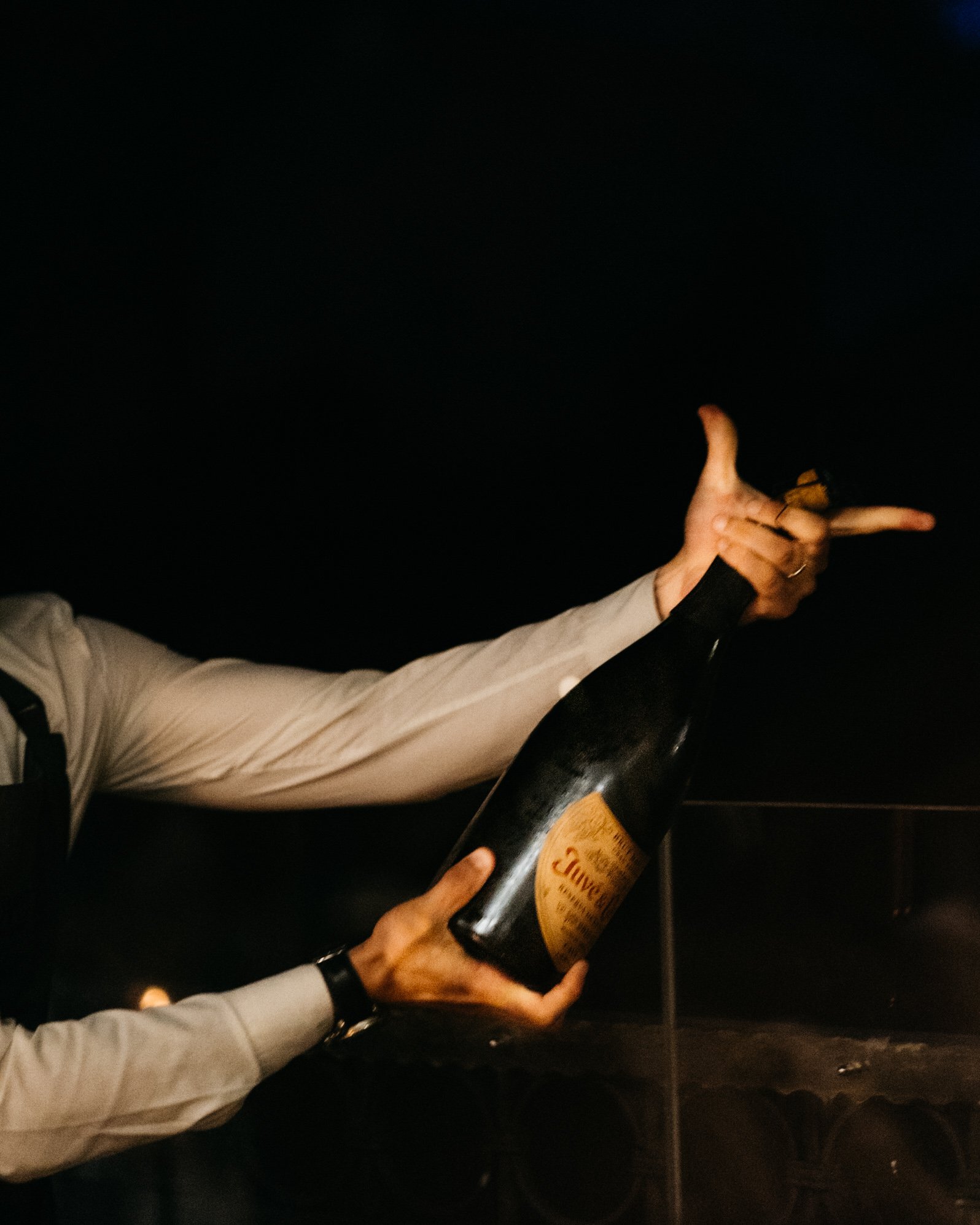 Person holding a Dom Pérignon champagne bottle against a dark background.
