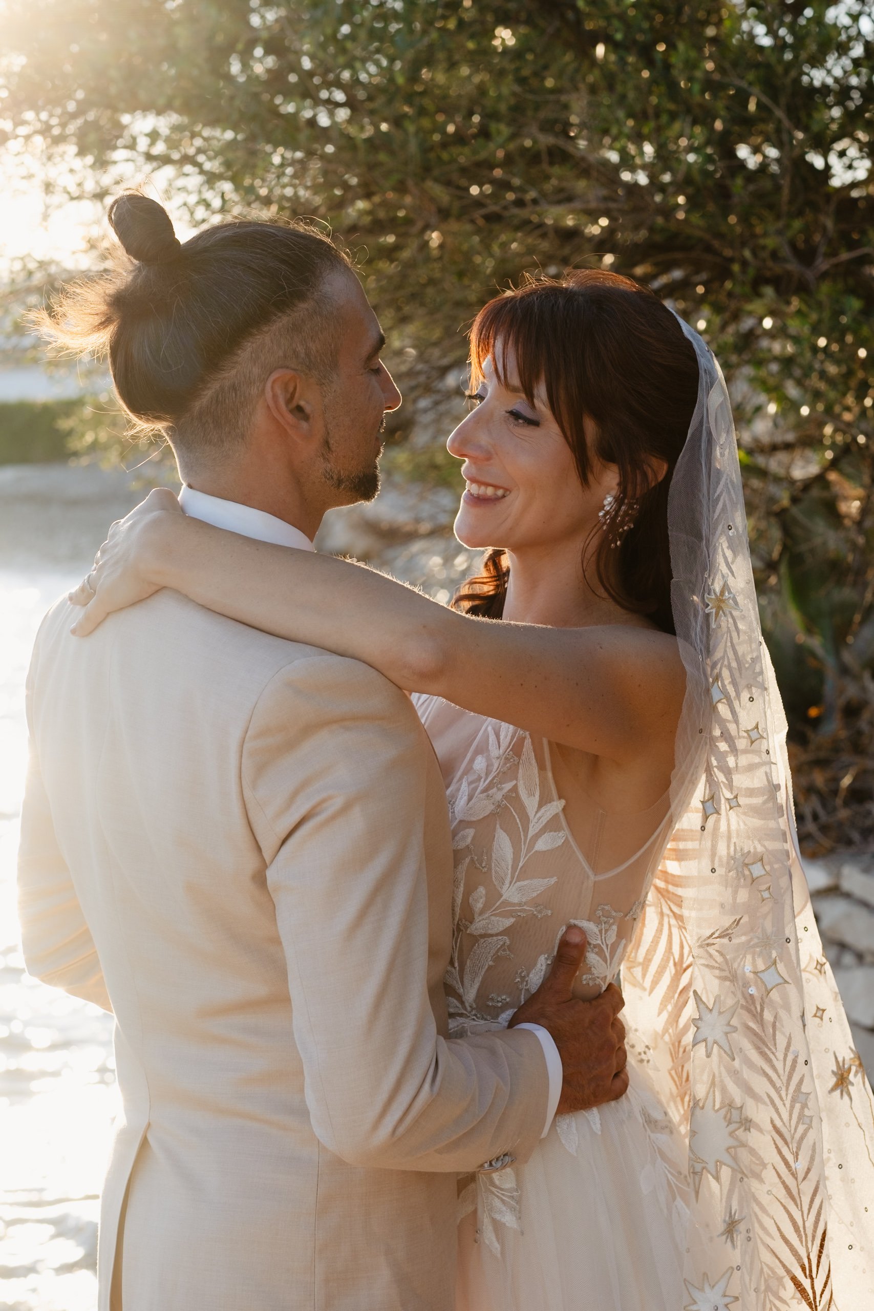 Bride and groom embracing with a sunlit background.