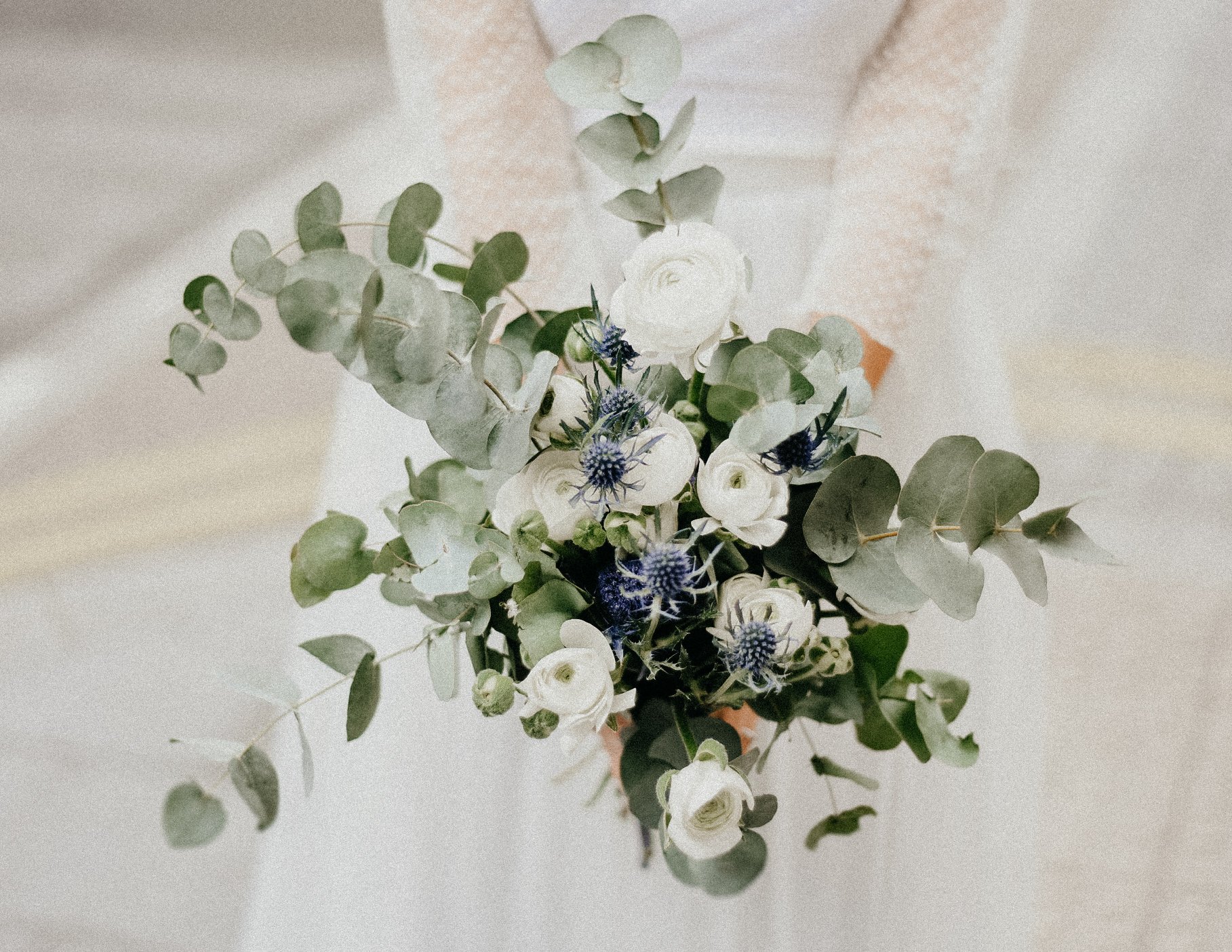 Bride holding white and blue floral bouquet with eucalyptus leaves