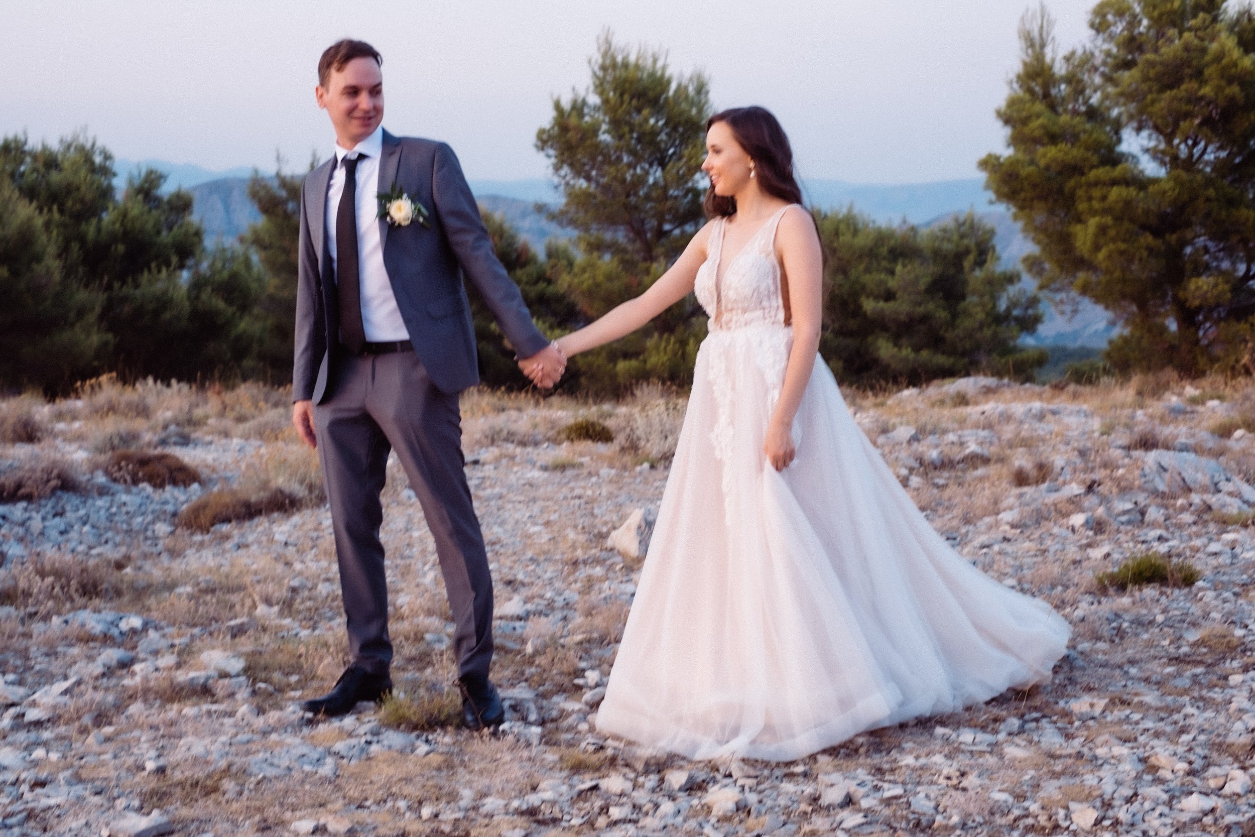 Bride and groom holding hands outdoors at the mount Srd above Dubrovnik town.