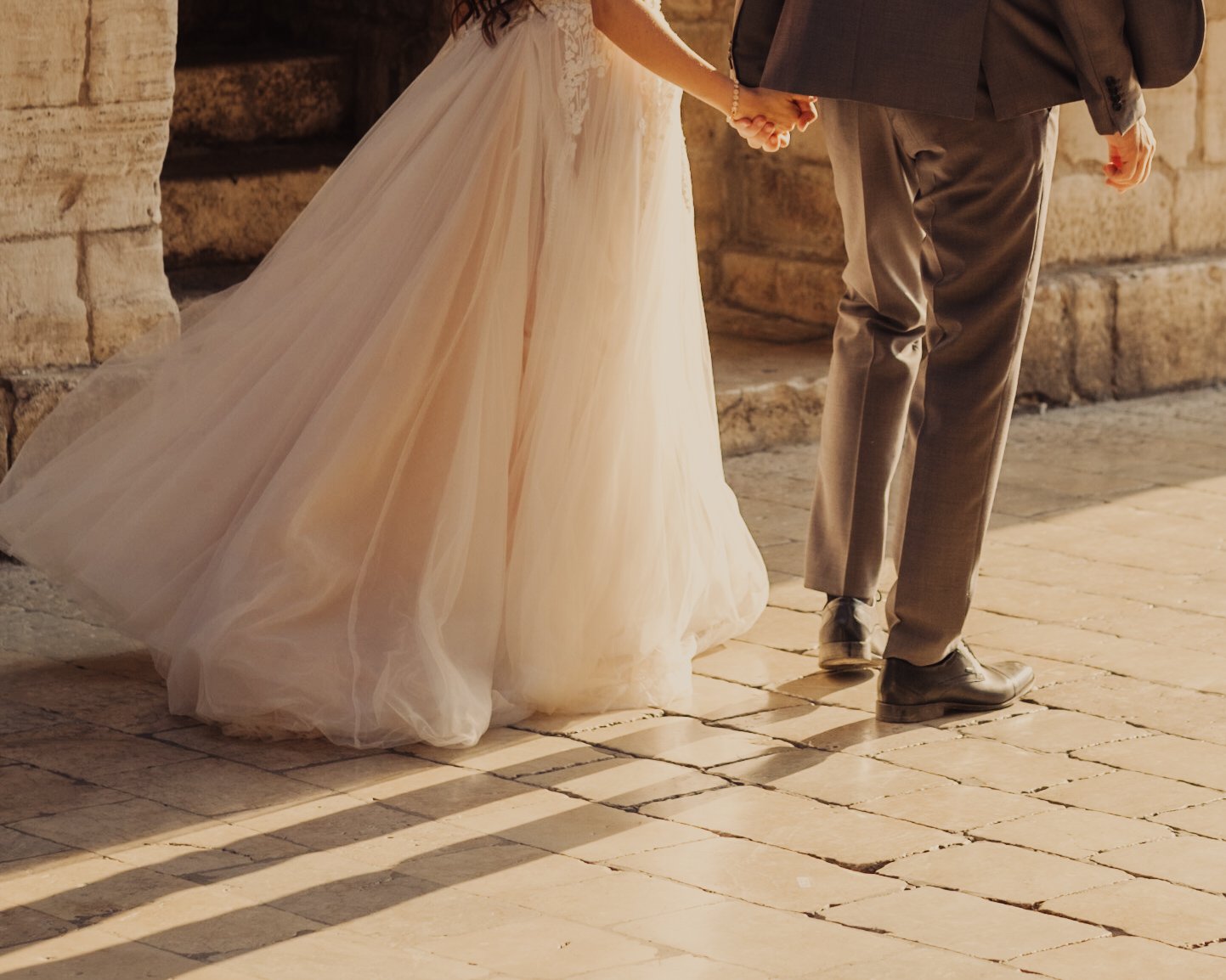 Bride and groom holding hands in warm light.