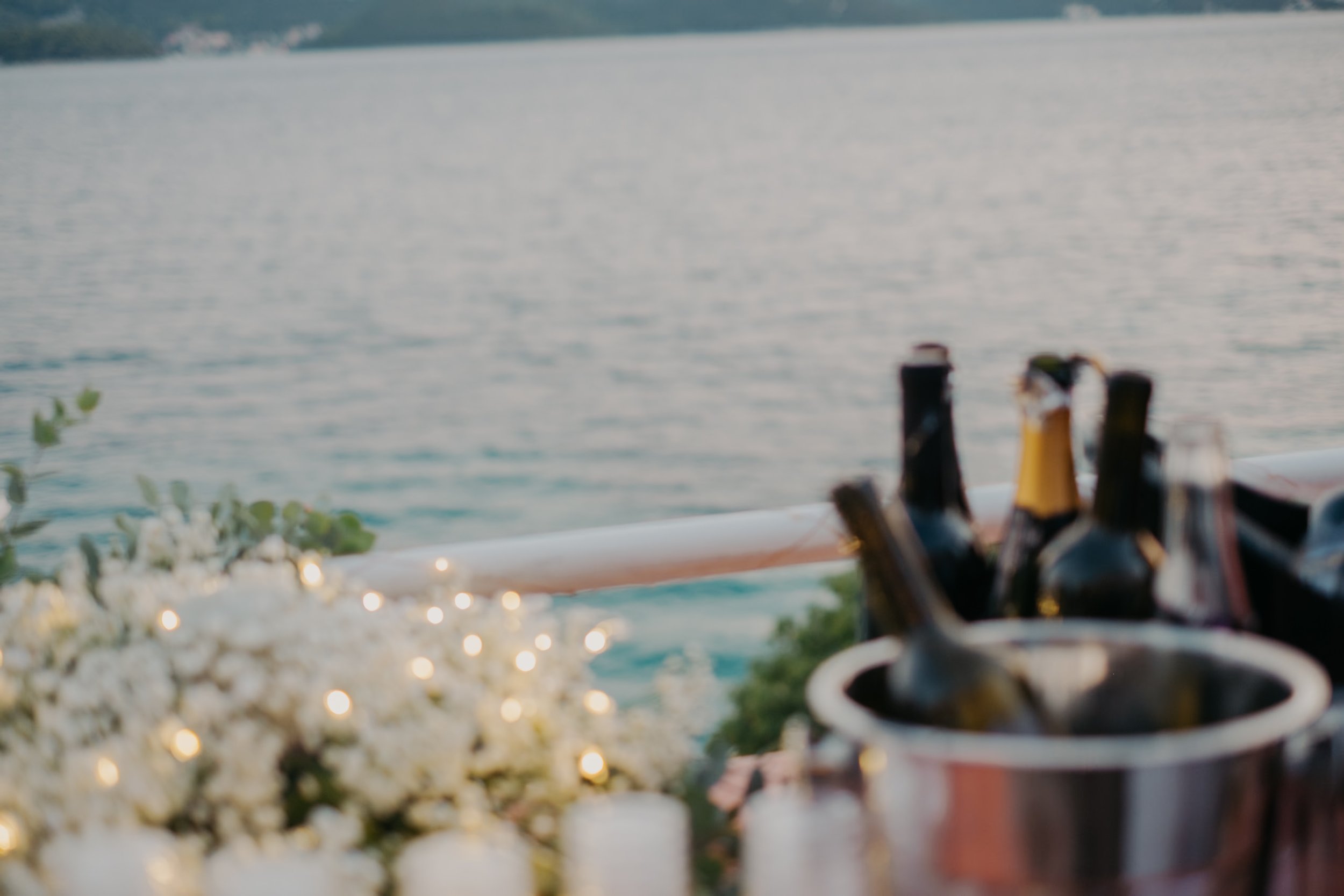Blurry image of a lakeside view with wine bottles and flowers