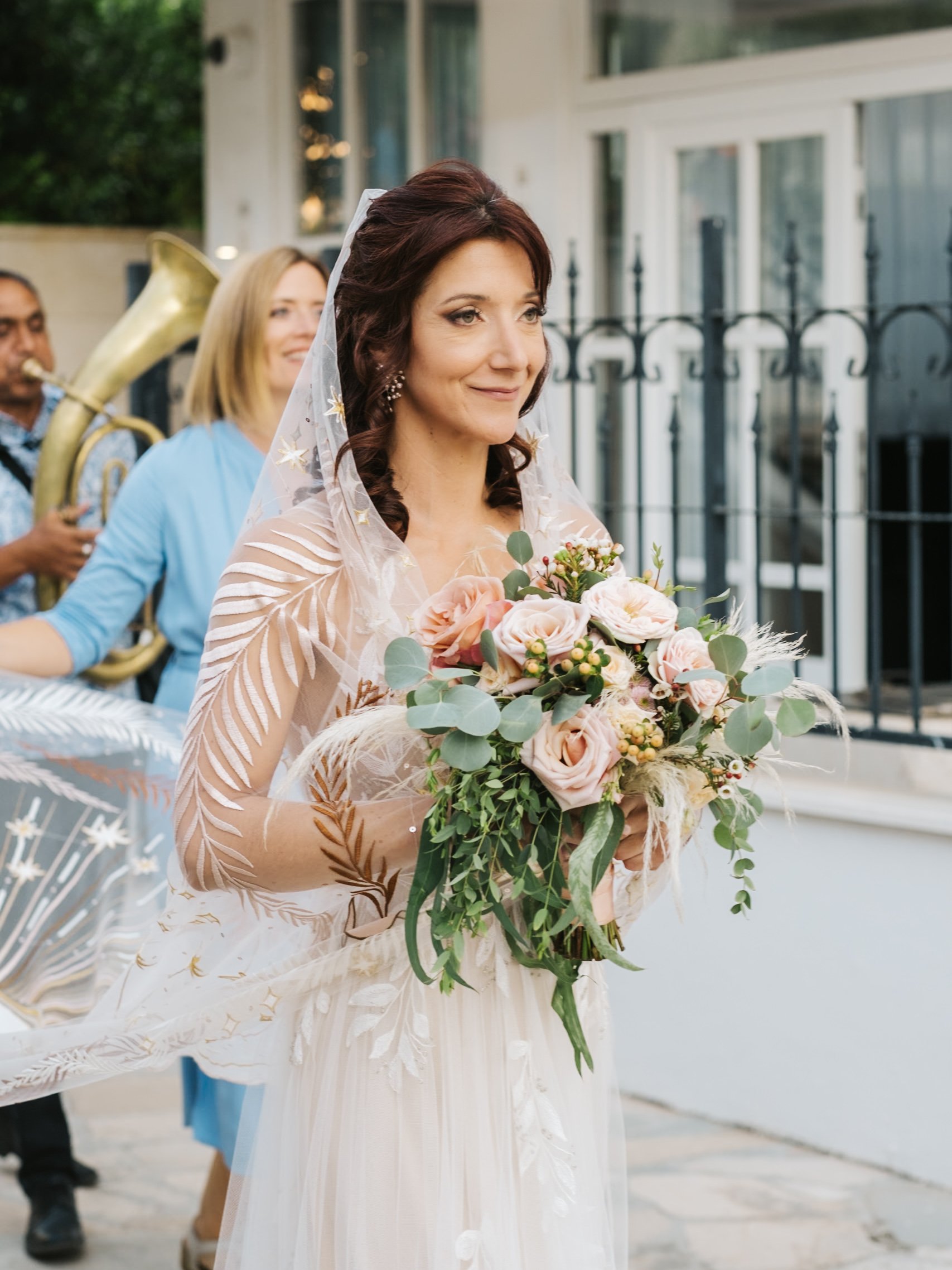 Bride holding a bouquet with musicians in the background.