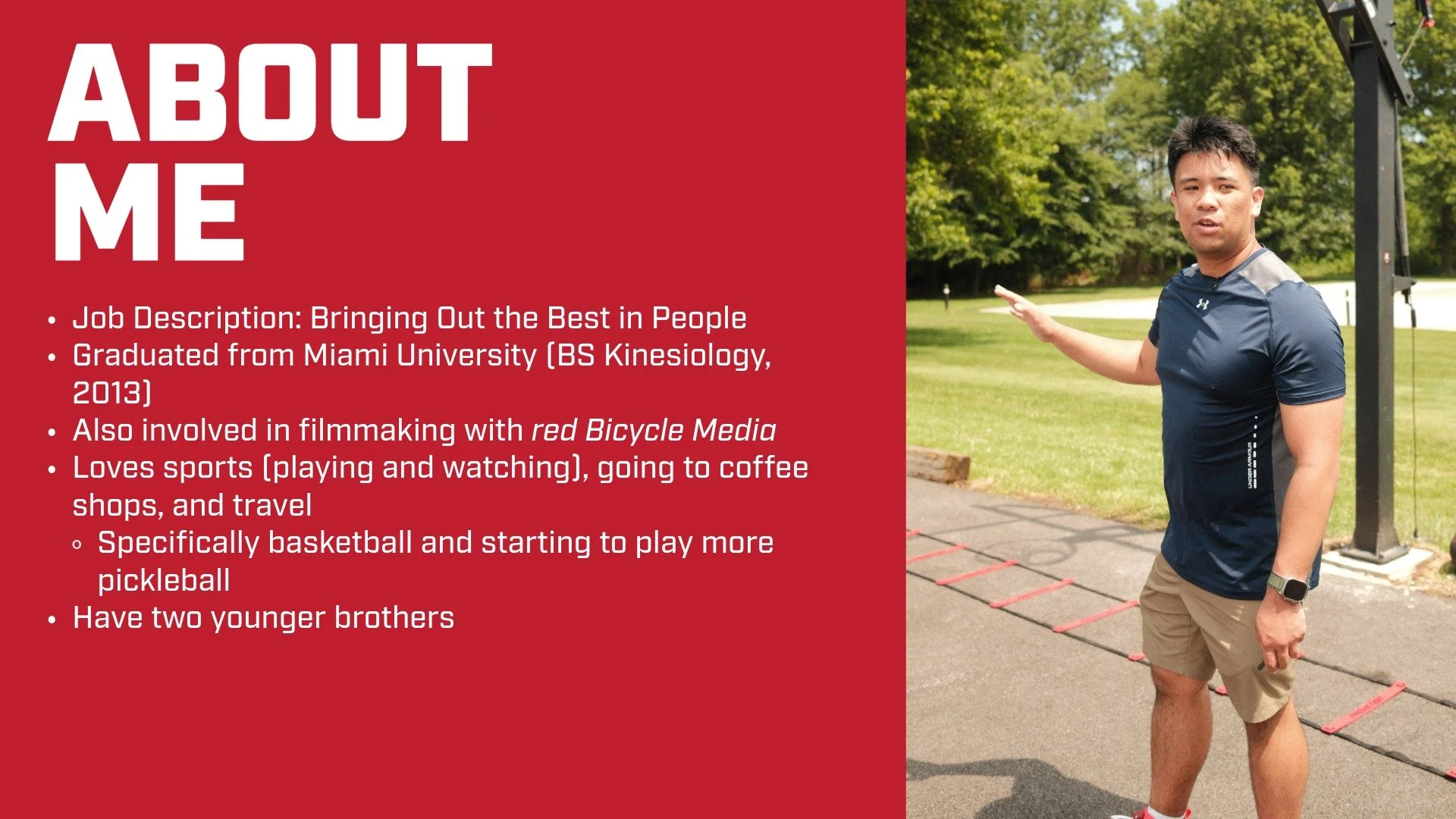 A man in athletic clothing pointing to his personal introduction slide on a red background, with outdoor park scenery and exercise equipment in the background.