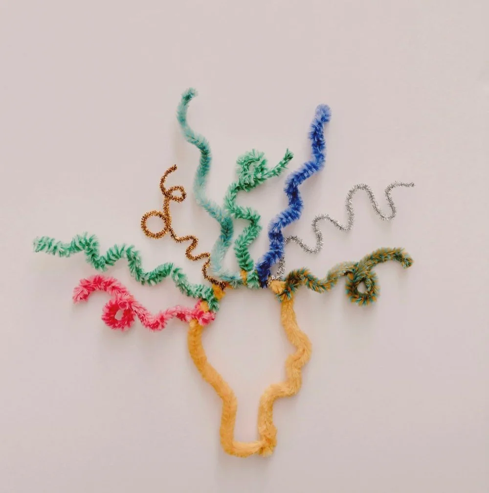 Colorful pipe cleaner worms arranged in a star shape on a white background.