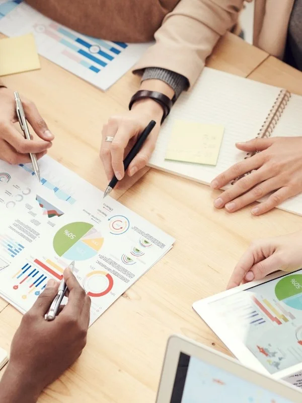 People reviewing financial charts and graphs on documents during a meeting.