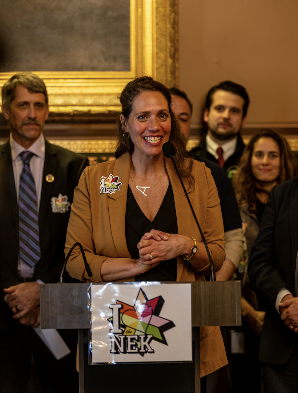 Abby long standing in front of a podium smiling