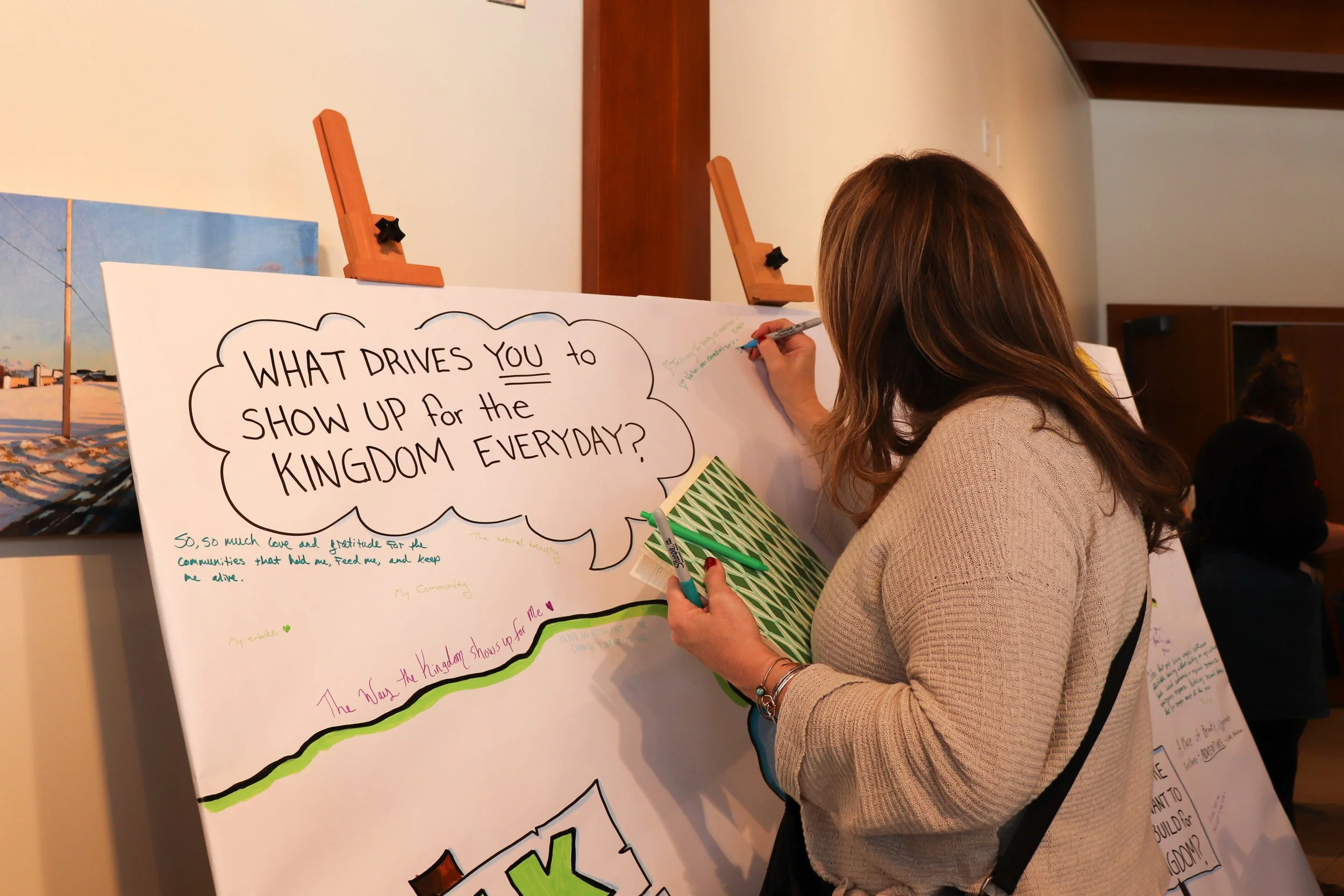 woman writing on a board that says, "what drives you to show up for the kingdom everyday?"