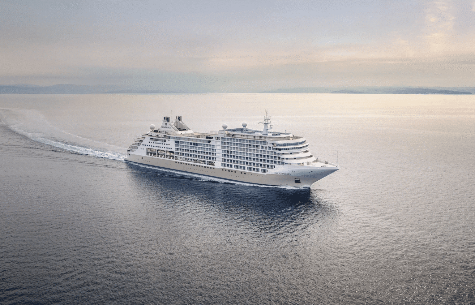 Großer Kreuzfahrtschiff auf offenem Meer, im Hintergrund Horizont und Himmel, ruhiges Wasser, sonniger Himmel