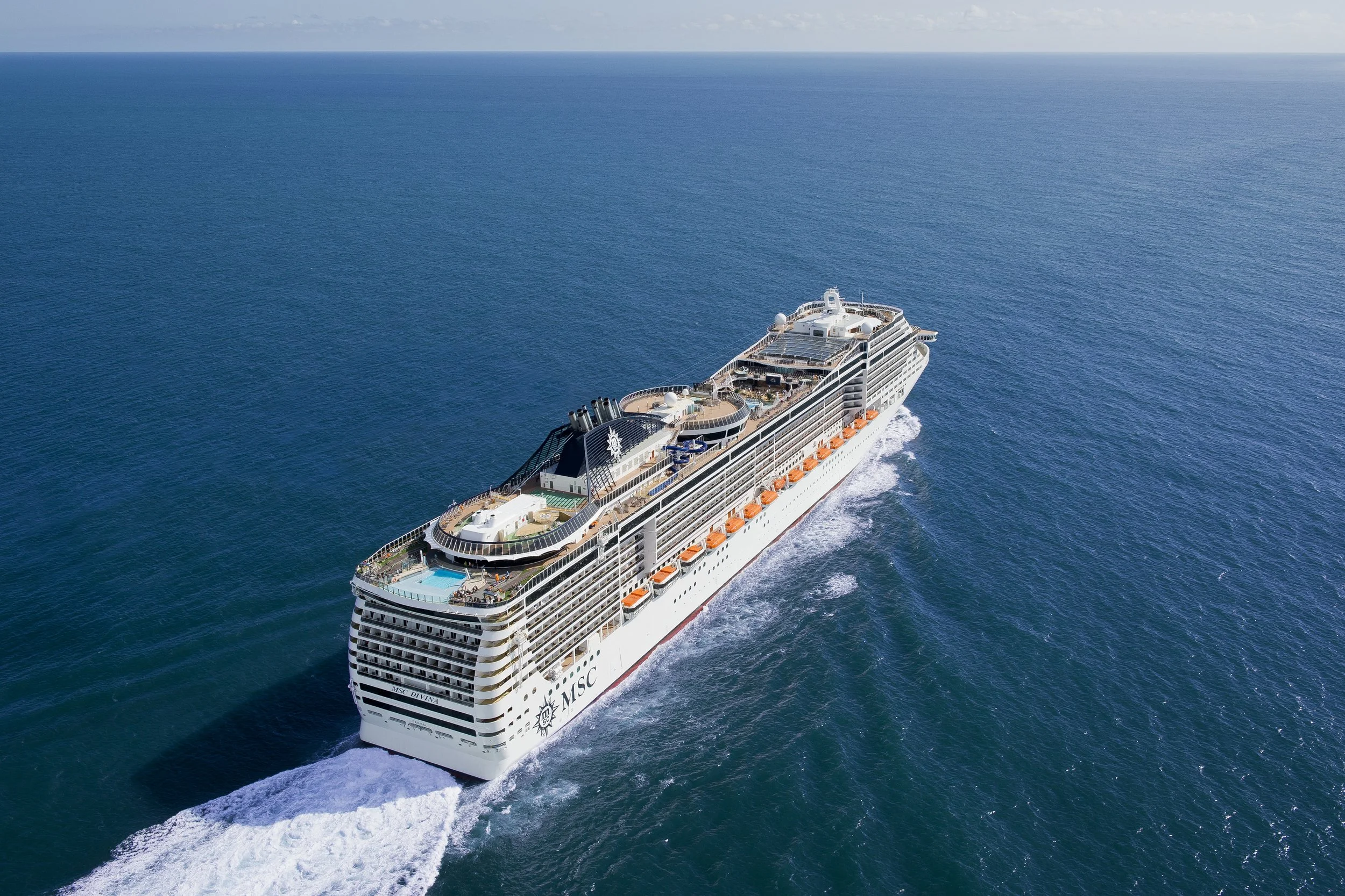 Ein großes Kreuzfahrtschiff mit mehreren Decks fährt auf dem offenen Meer.