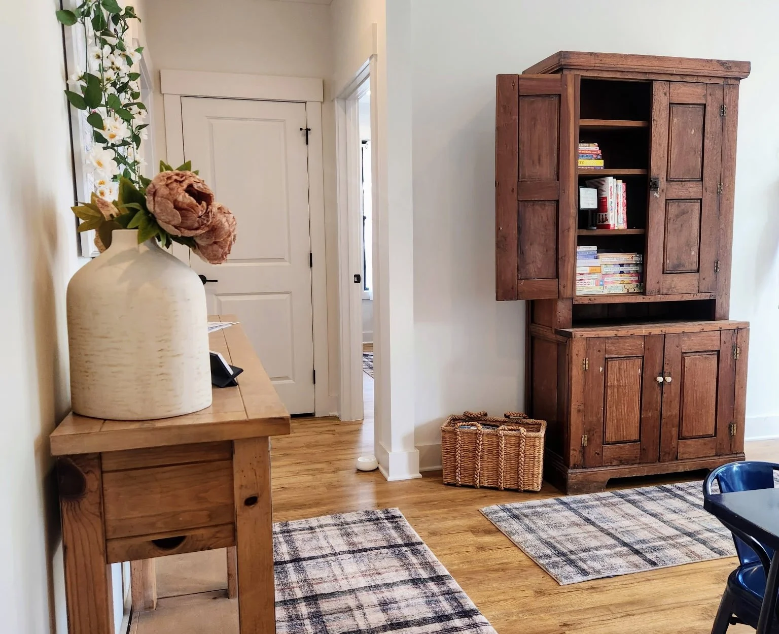 room with white walls large vase and wooden hutch