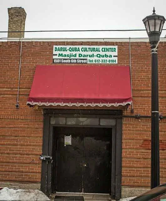 The exterior of a brown brick building with a sign over the door that says Dural-Queba Cultural Center Masjid Dural Quba 1501 South 6th Street Tel: 612-332-0104.