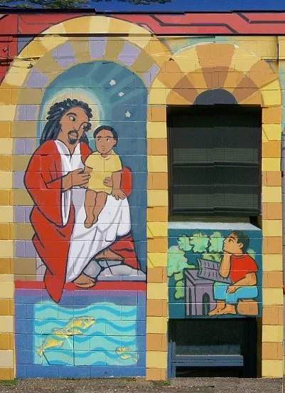 A painting of Jesus holding a young child and another painting of a person gazing upward with a book in front of him.