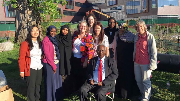 A diverse group of people smiling and posing outside on a green lawn. 