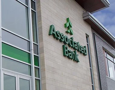 The exterior of a bank, with the name on wall, Associated Bank.