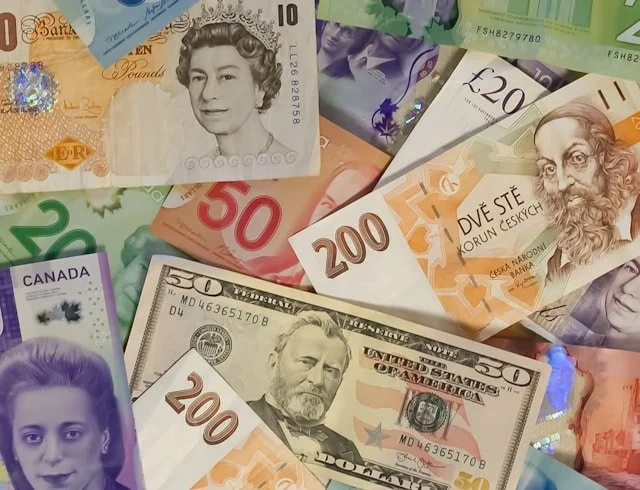 Paper currency from different countries scattered onto a surface.