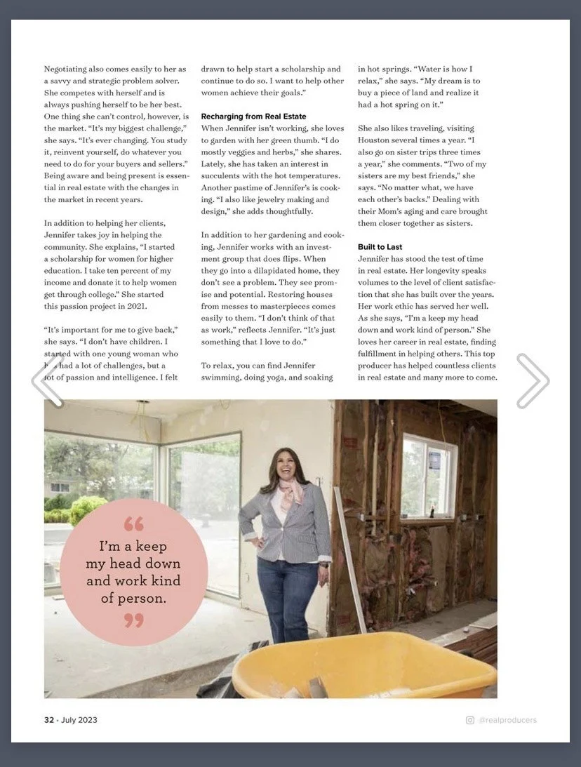 A woman standing inside a house under construction, dressed in a blazer and jeans, smiling at the camera, with a window and unfinished walls behind her; a yellow construction bucket in the foreground.