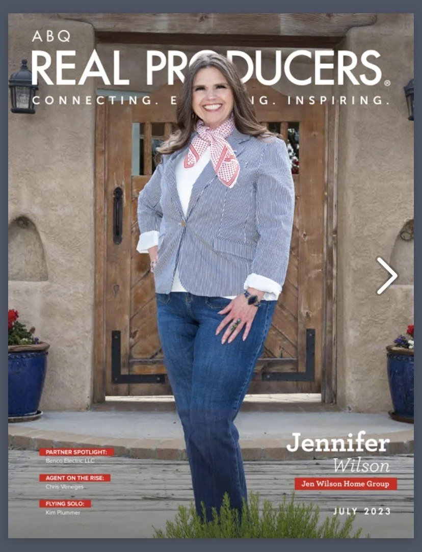 Magazine cover featuring a smiling woman in a blazer and jeans standing outside in front of a wooden door with potted plants nearby. The magazine is titled "ABQ Real Producers" and the woman is identified as Jennifer Wilson from Jen Wilson Home Group, July 2023 issue.