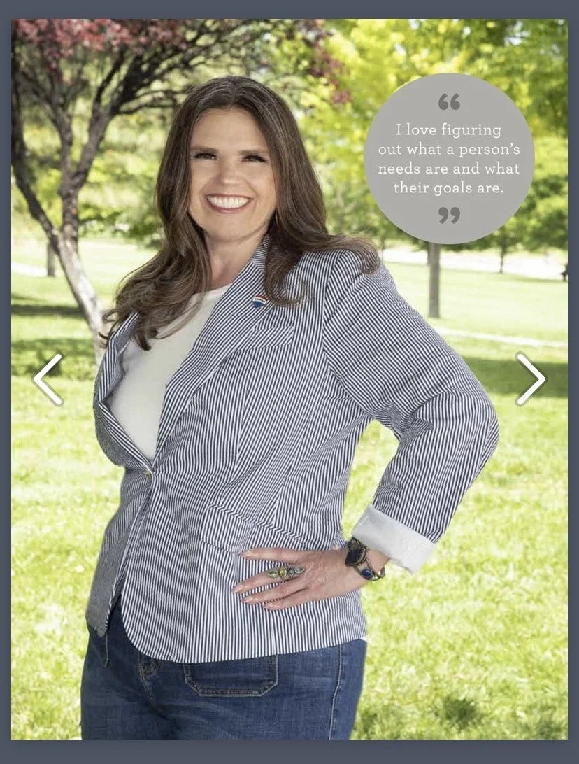 A woman with brown hair smiling, standing outdoors in a park with green trees in the background. She wears a striped blazer over a white shirt, with her right hand on her hip. There is a quote in a gray circle that says, "I love figuring out what a person's needs are and what their goals are."