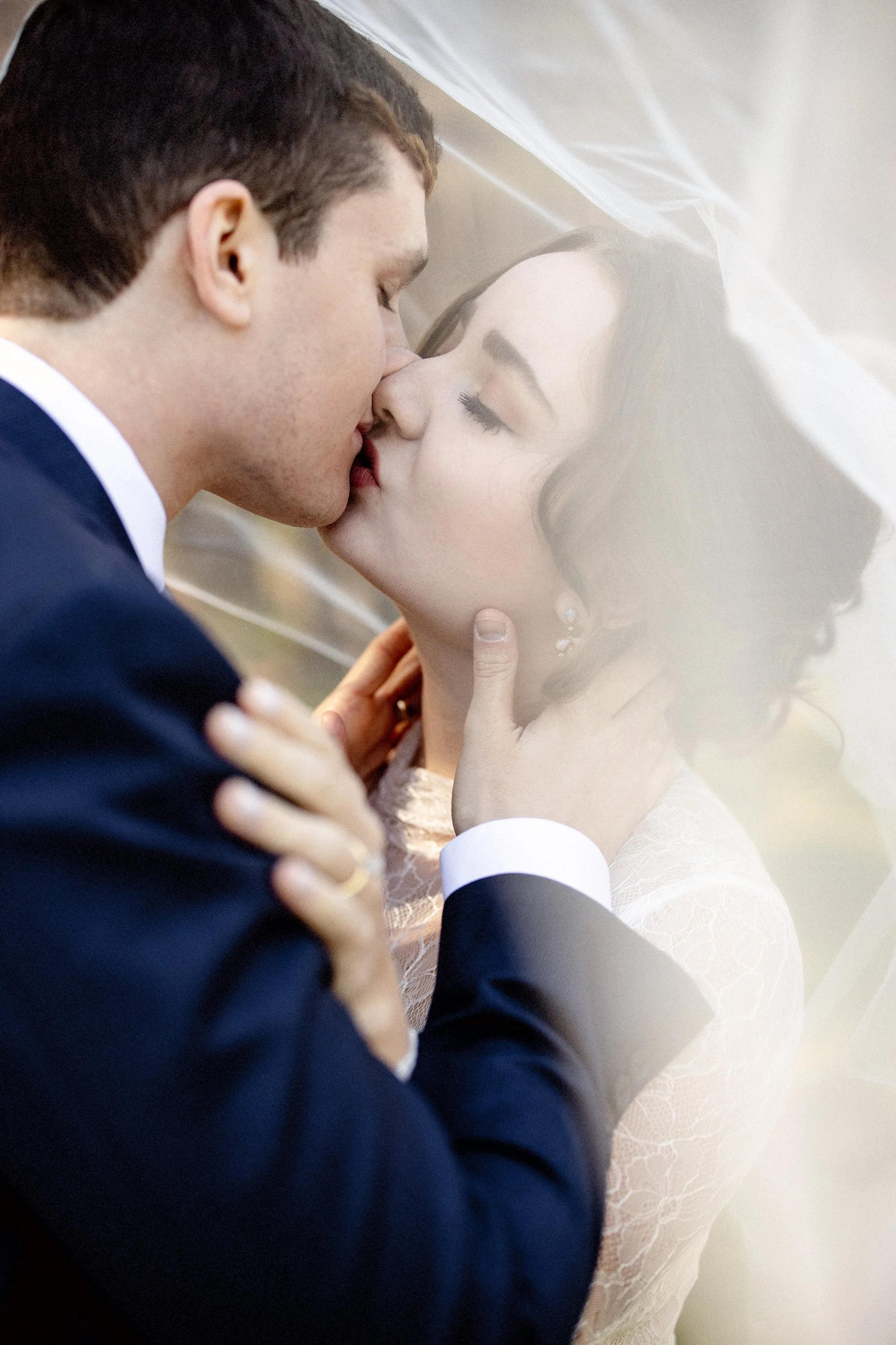 A man and woman in wedding attire sharing a kiss.