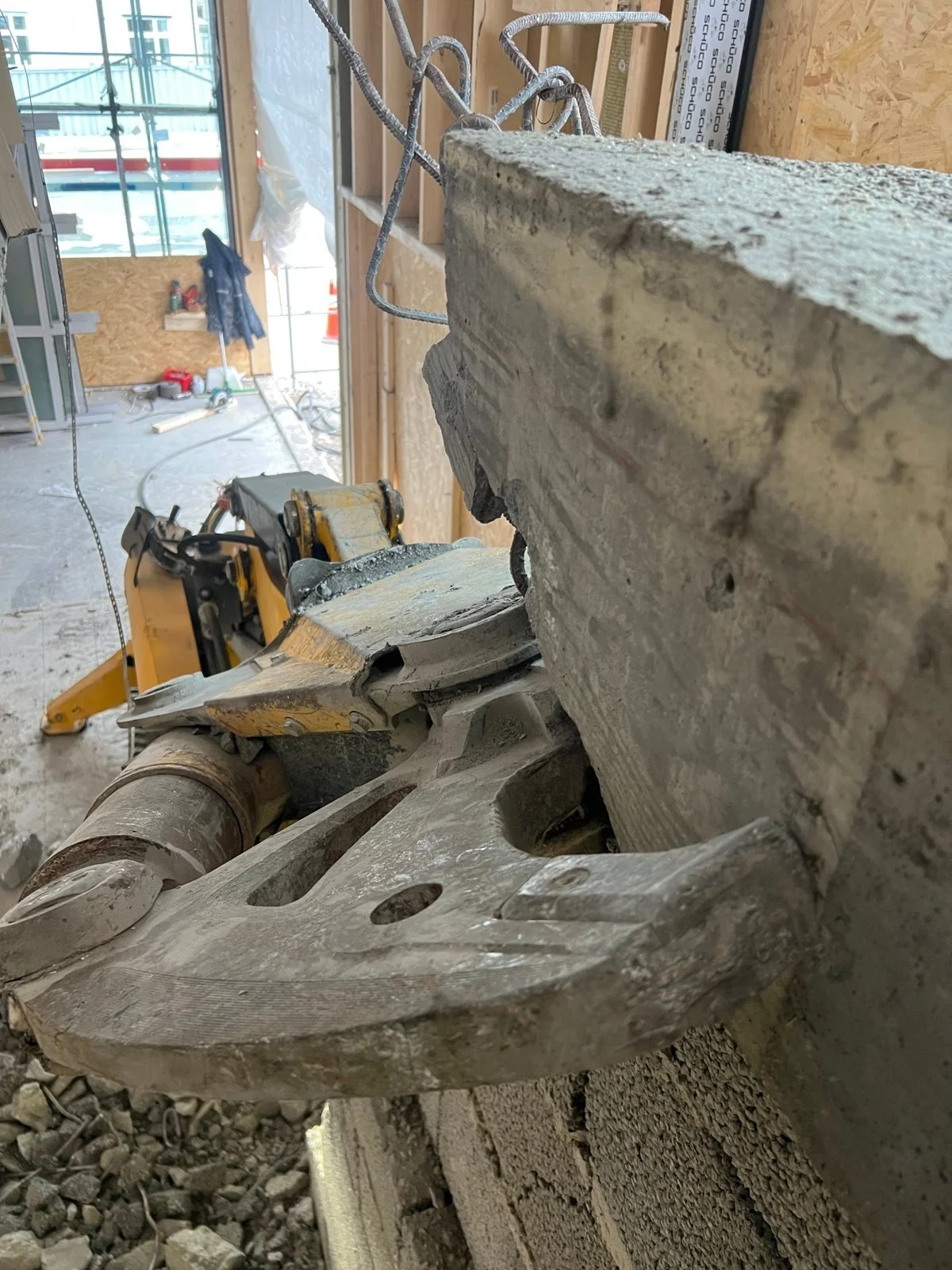 Brokk med betongsaks klipper ned betong inne i butikk