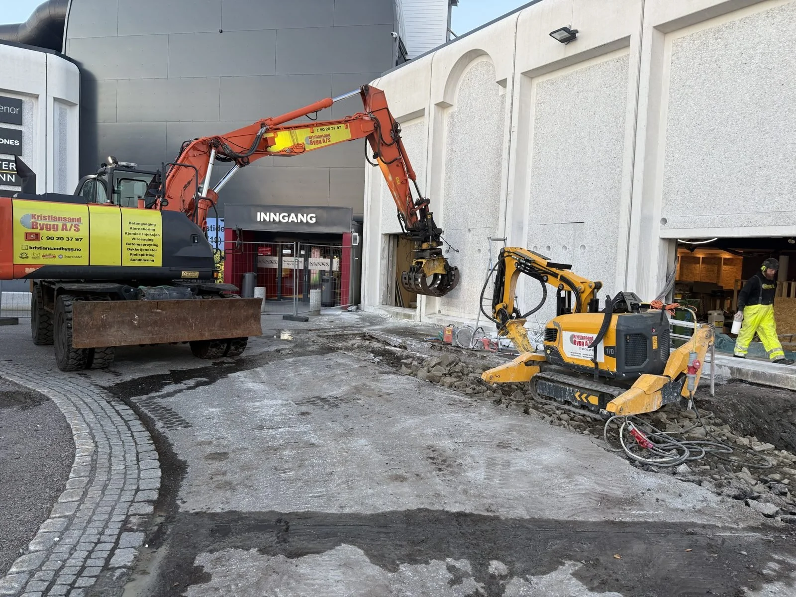 Brokk rivemaskin ved butikkinngang under rivearbeid