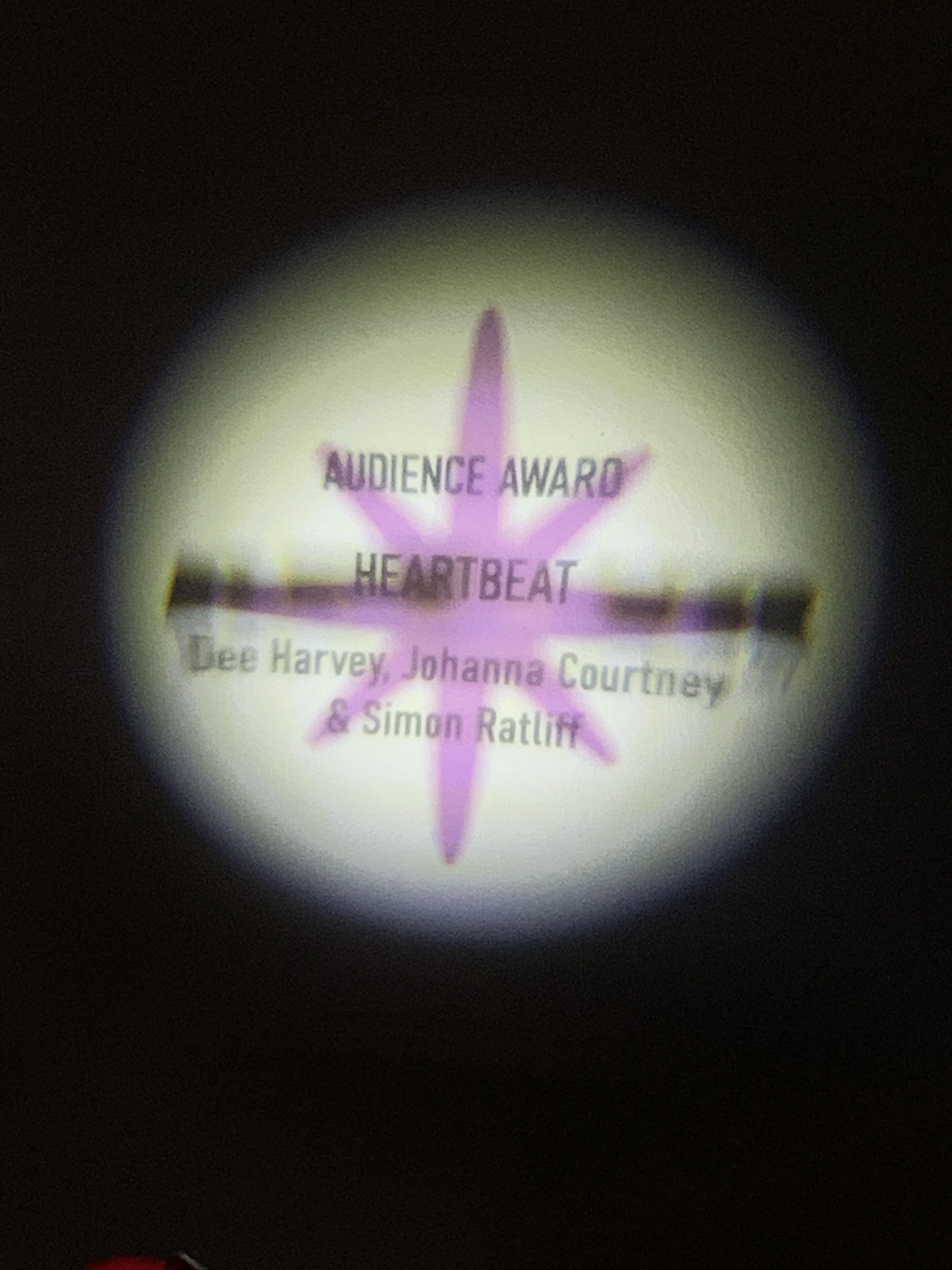 A wall projection image with a purple star announcing the winner of the Audience Award at ART*VR 2024, with the words 'Audience Award' and 'Heartbeat'.