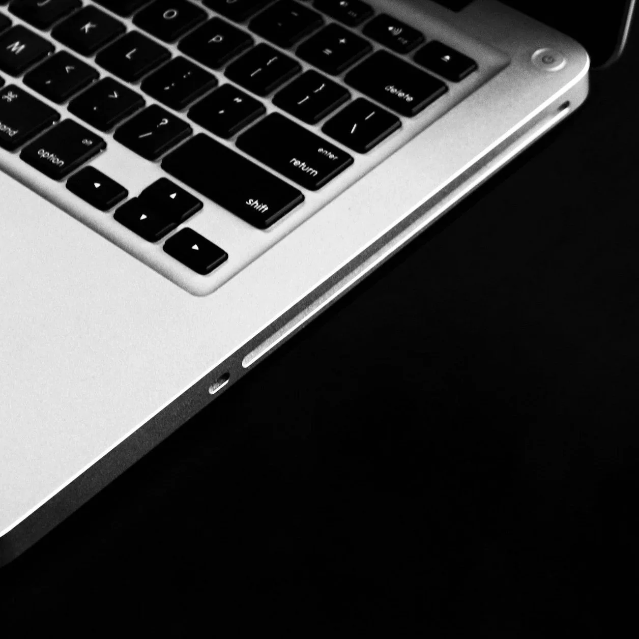 Close-up of a silver laptop keyboard on a black background.