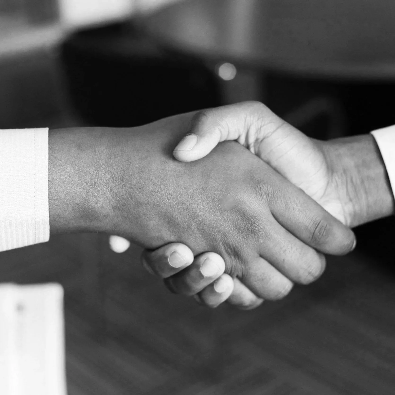 Close-up of two hands shaking, one appears to be male and the other female, in black and white.
